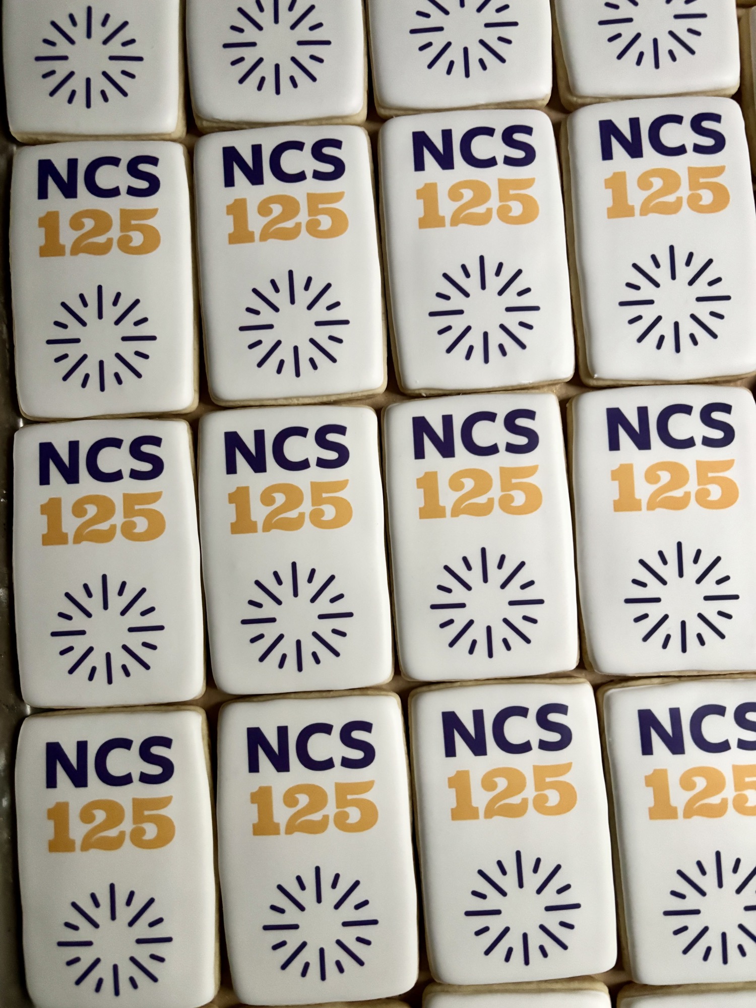 Rectangular white cookies printed in navy and gold with an anniversary mark and a starburst.