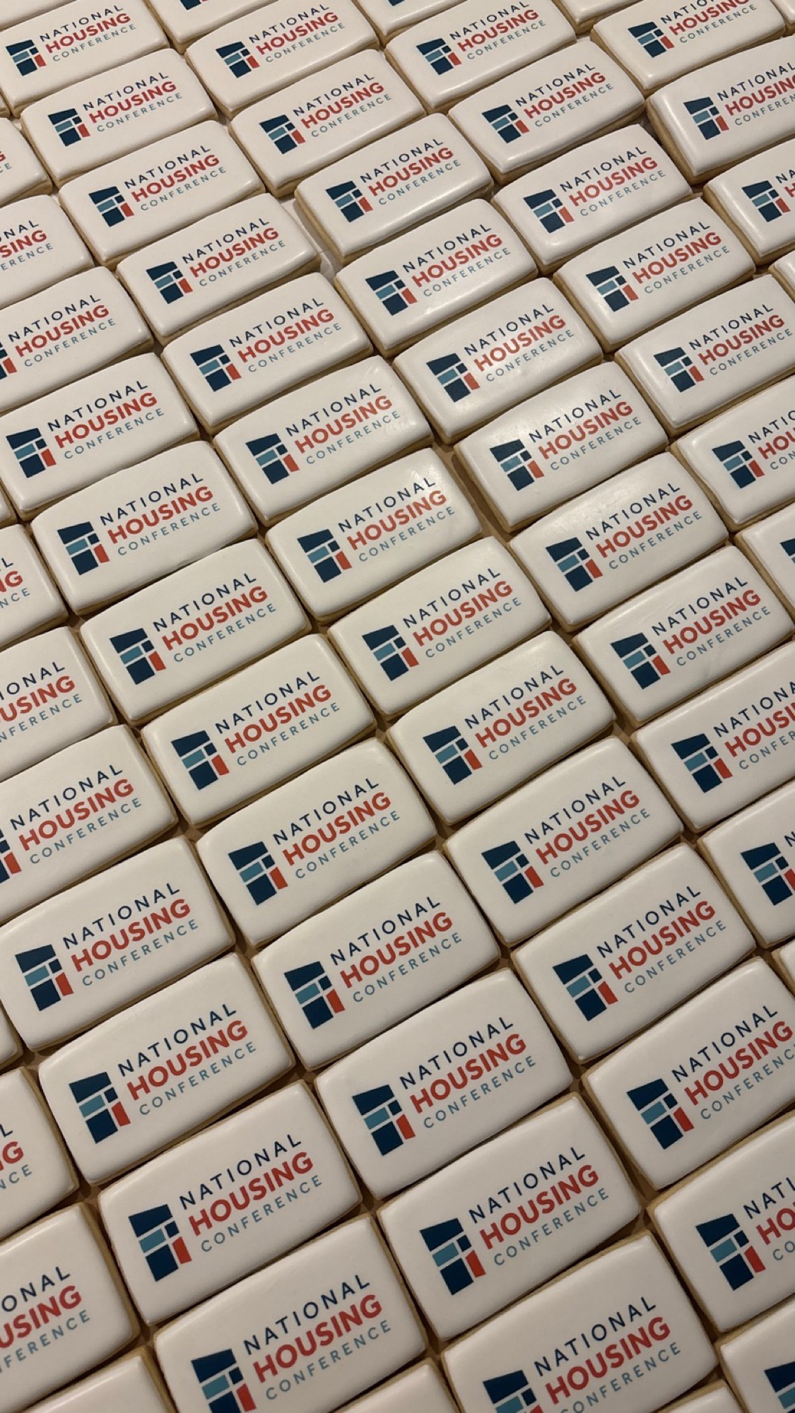 Rows of white rectangular cookies printed with a conference logo in navy and red.